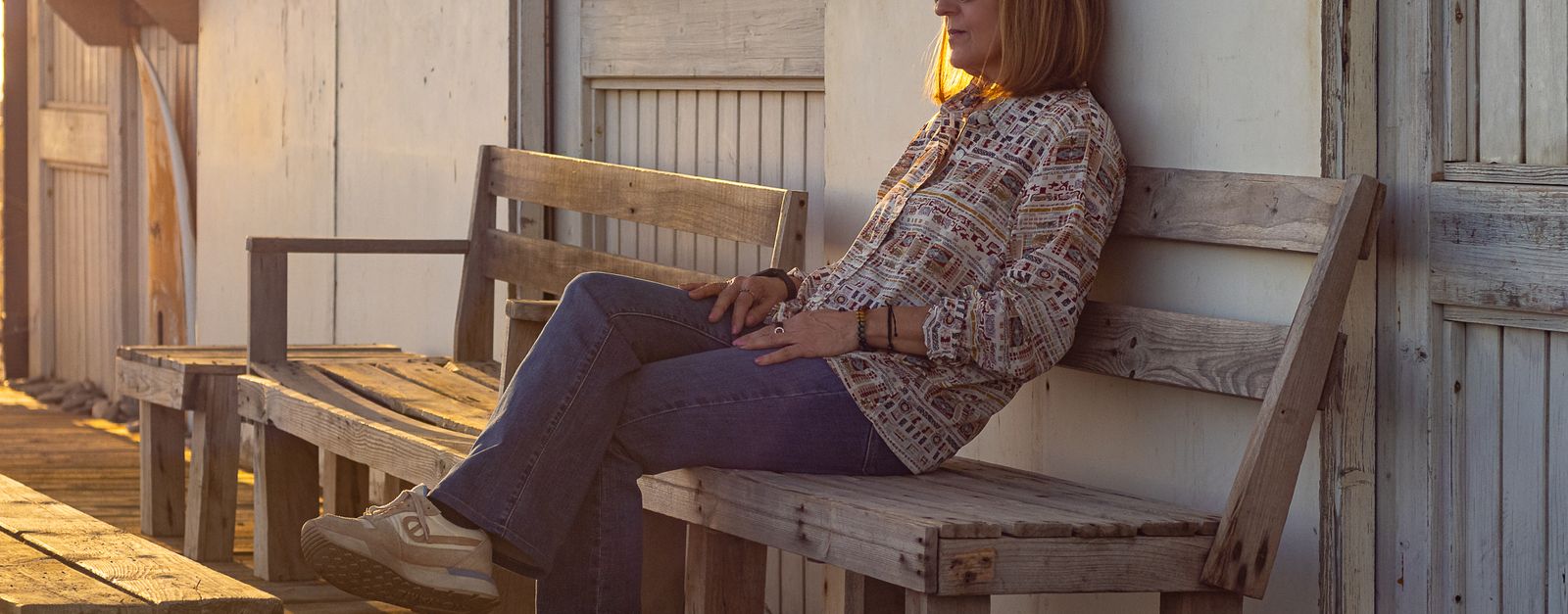 A woman sitting on a wooden bench in Motril, enjoying a sunny urban environment.