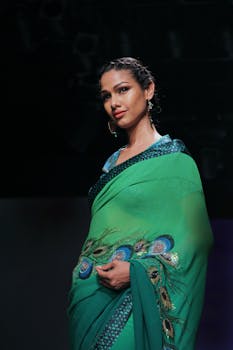 一位时尚女性身着充满活力的绿色纱丽，在T台上优雅地展现风采