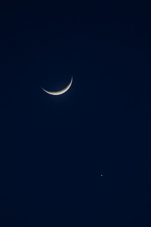 Free A tranquil crescent moon glows in a crisp clear night sky with a distant star. Stock Photo