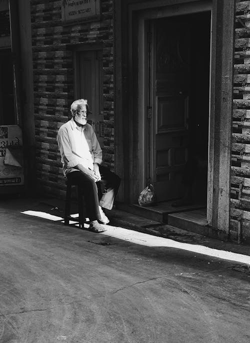 Man Sitting on Stool Outside the Building