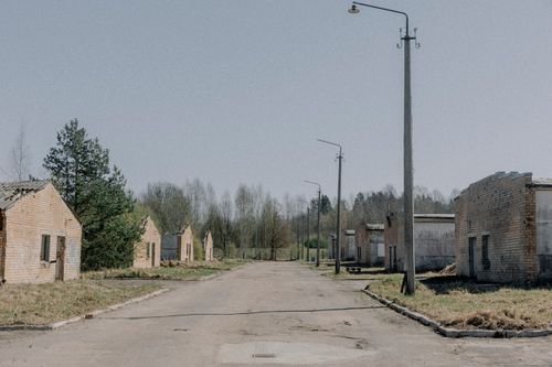 Free A desolate street lined with decaying brick buildings and overgrown vegetation. Stock Photo