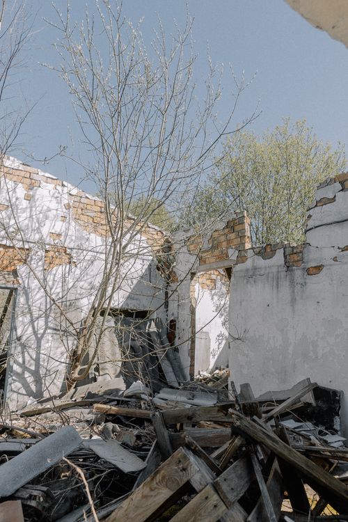 Free Abandoned structure with exposed brick and overgrown debris under a clear sky. Stock Photo