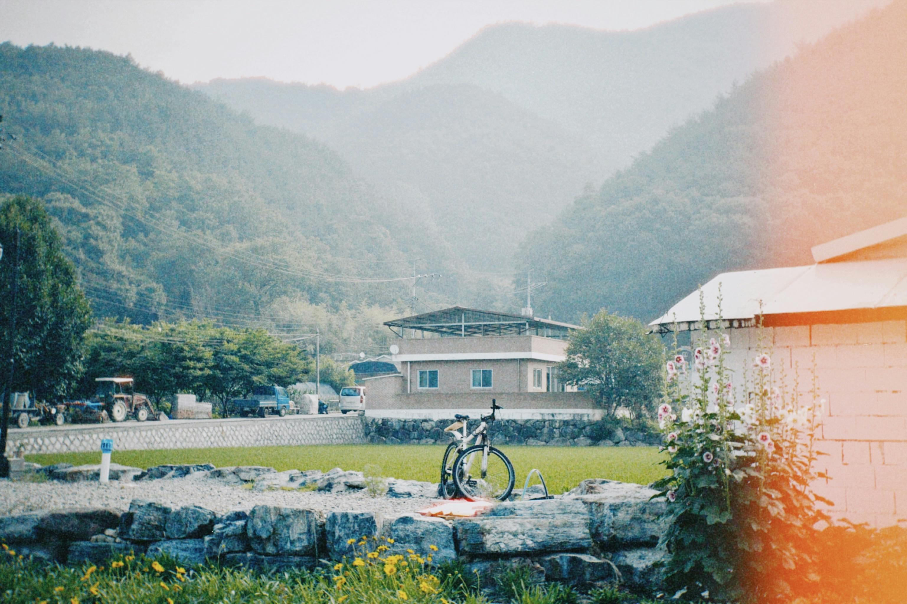 박보검과 곽동연이 '보검 매직컬' 세트에서 웃으며 대화하는 장면, 시골 마을 배경에 따뜻한 분위기와 함께 손하트 포즈