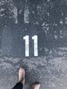 Person Standing On Concrete Floor With Number 11 Paint