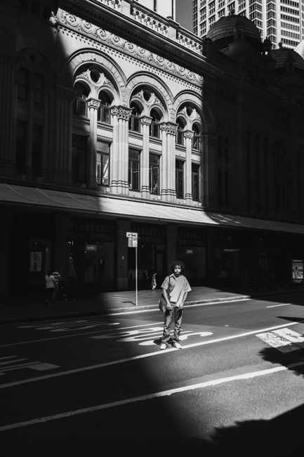 A man standing in the spotlight on an urban city street with architectural background in black and white.
