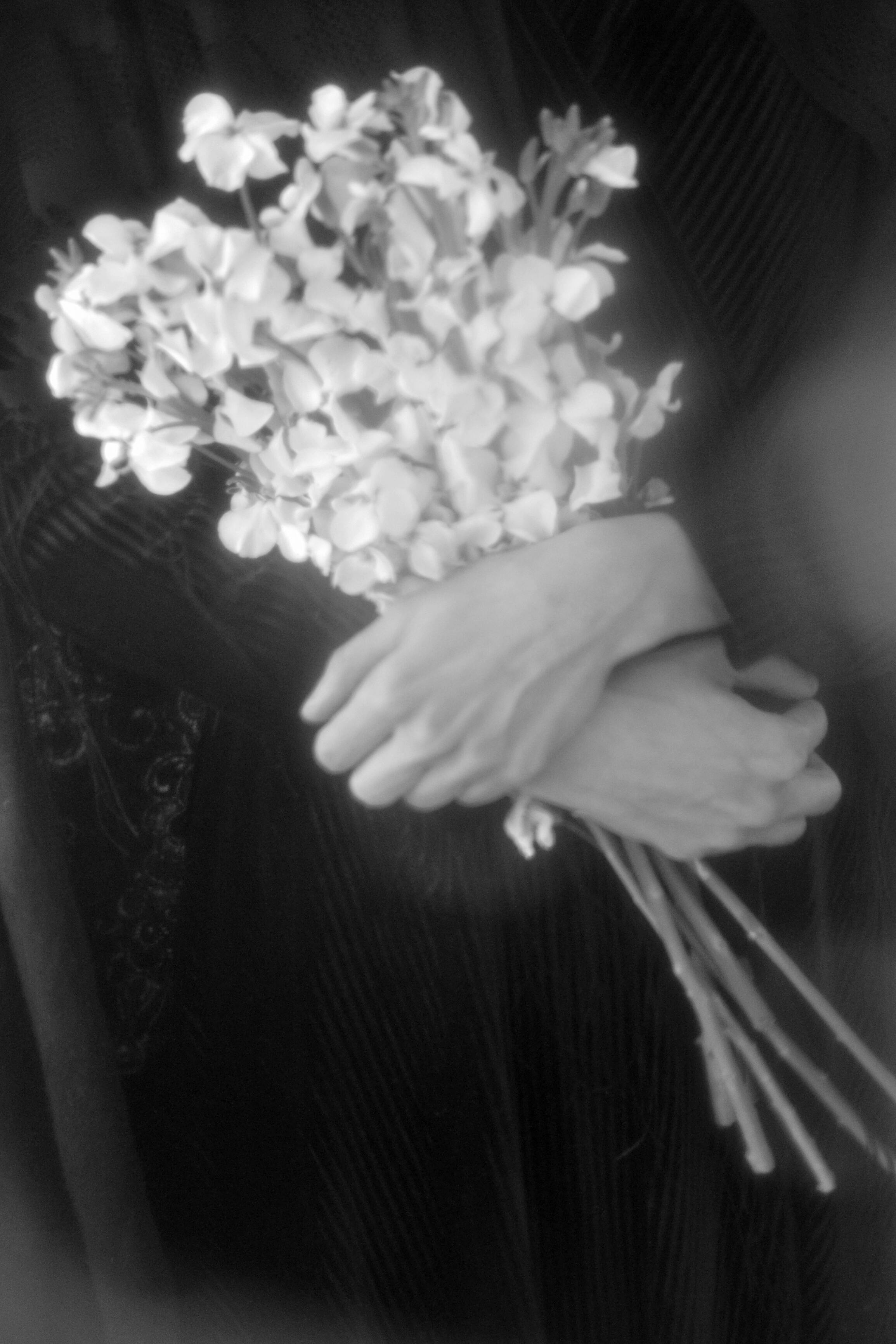 A black and white image of hands holding an elegant floral bouquet, exuding timeless elegance.
