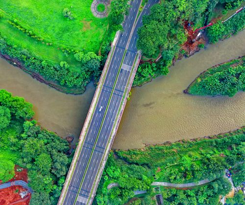 Free Aerial shot of a bridge over a winding river in Sindang Jaya, Indonesia, amidst lush greenery. Stock Photo