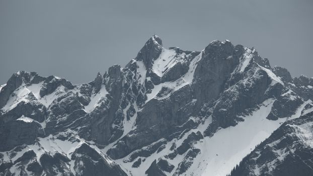 A grayscale photo showcasing majestic snowcapped mountain peaks under a cloudy sky.