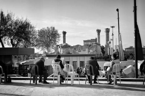 Men Sitting on Chairs in Town