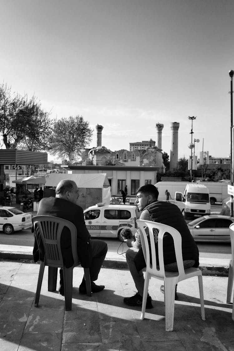 Men Sitting On Chairs In Town And Talking