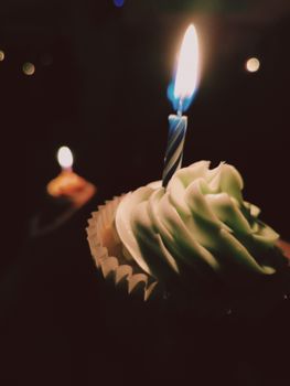 Beautiful cupcake with a single lit candle, symbolizing celebration and warmth.