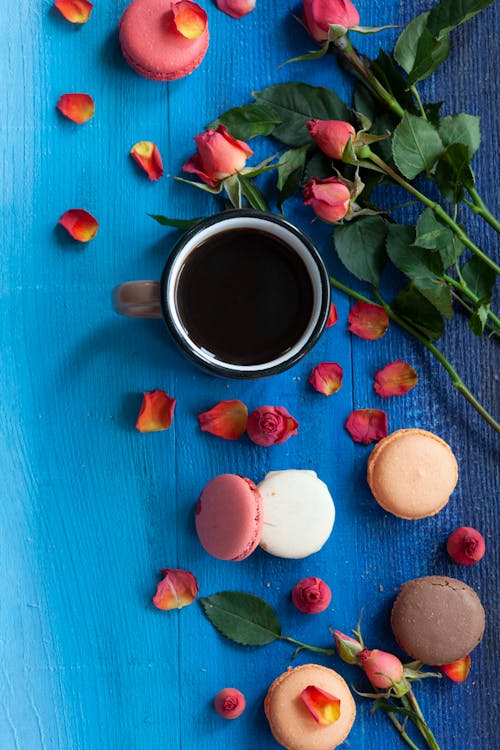 Black Coffee, Macaroons and Flowers on Blue Table