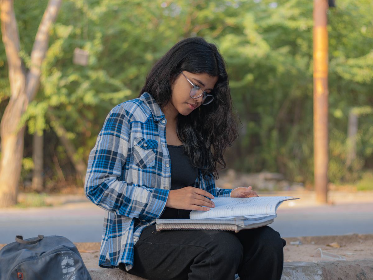 Indian college student studying and making notes outdoors in Delhi