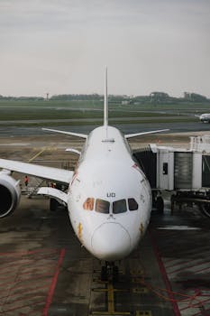 Front view of a parked commercial airplane on an airport tarmac, showcasing boarding bridge.