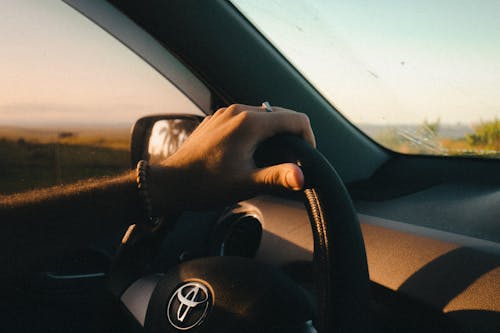 A person driving a car with the sun setting in the background