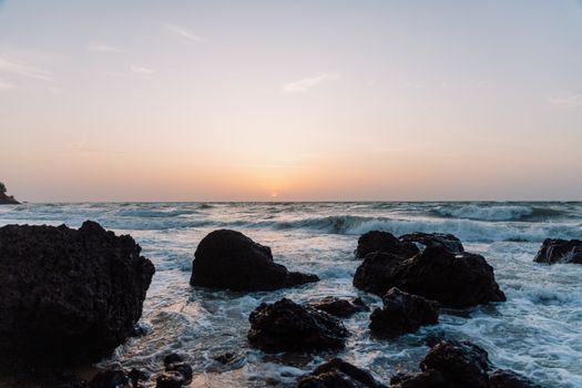 Experience the serene beauty of ocean waves crashing on a rocky beach at sunrise.