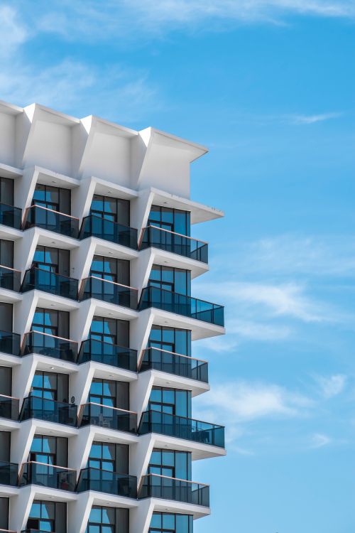 Free Contemporary Dubai apartment building with geometric balconies under clear blue sky. Stock Photo