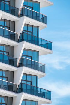 Close-up of a modern skyscraper in Dubai featuring geometric design and glass balconies against blue sky.