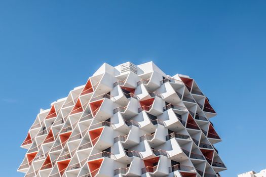 A contemporary architectural marvel in Dubai with geometric patterns against a bright blue sky.
