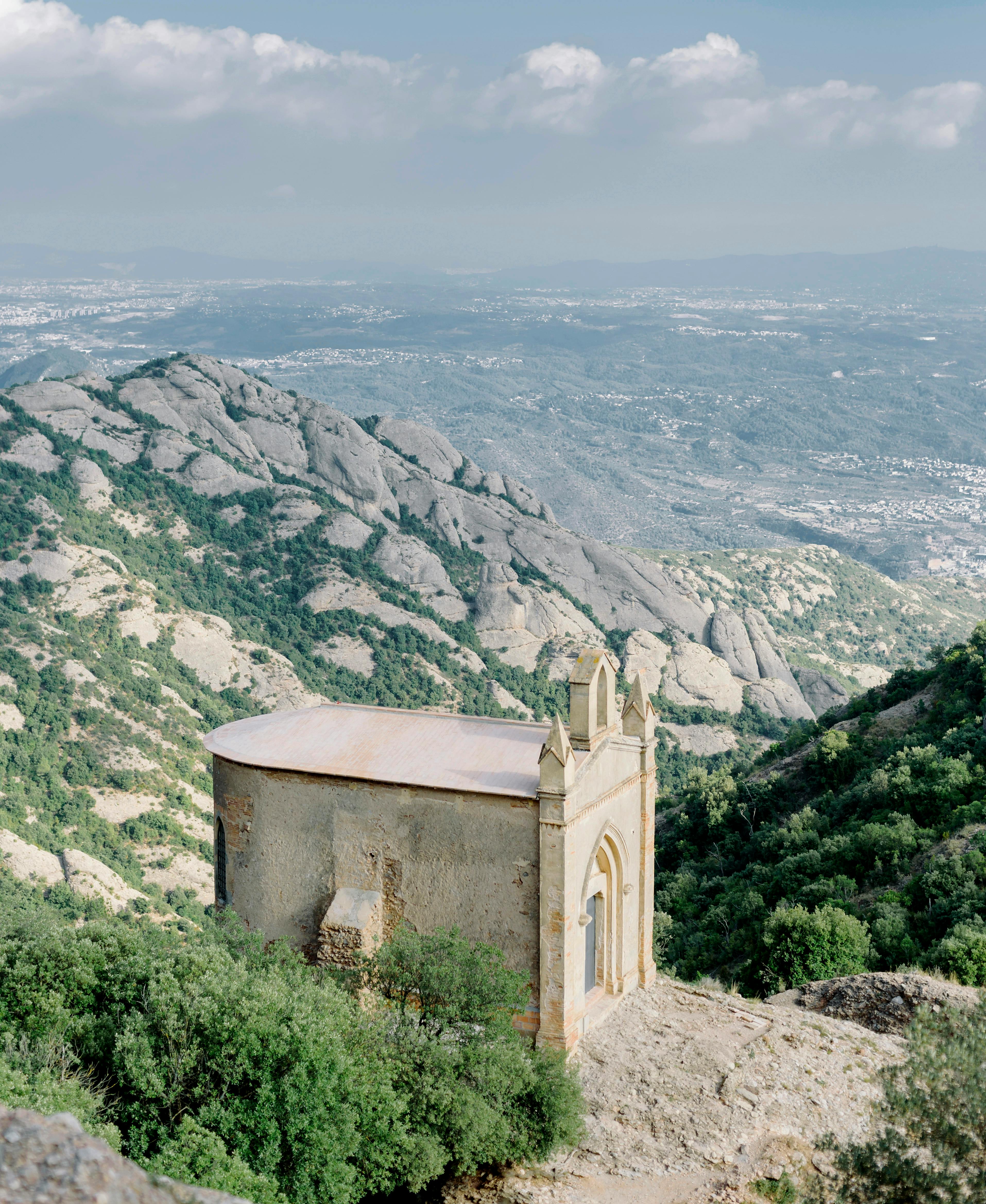 A picturesque chapel nestled in the Montserrat mountains with a view of lush green valleys.
