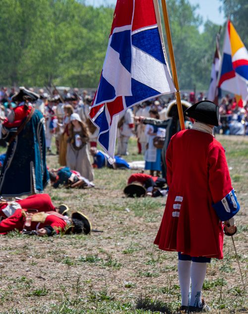 Free A vivid scene of a historical battle reenactment with people in period costumes and flags. Stock Photo