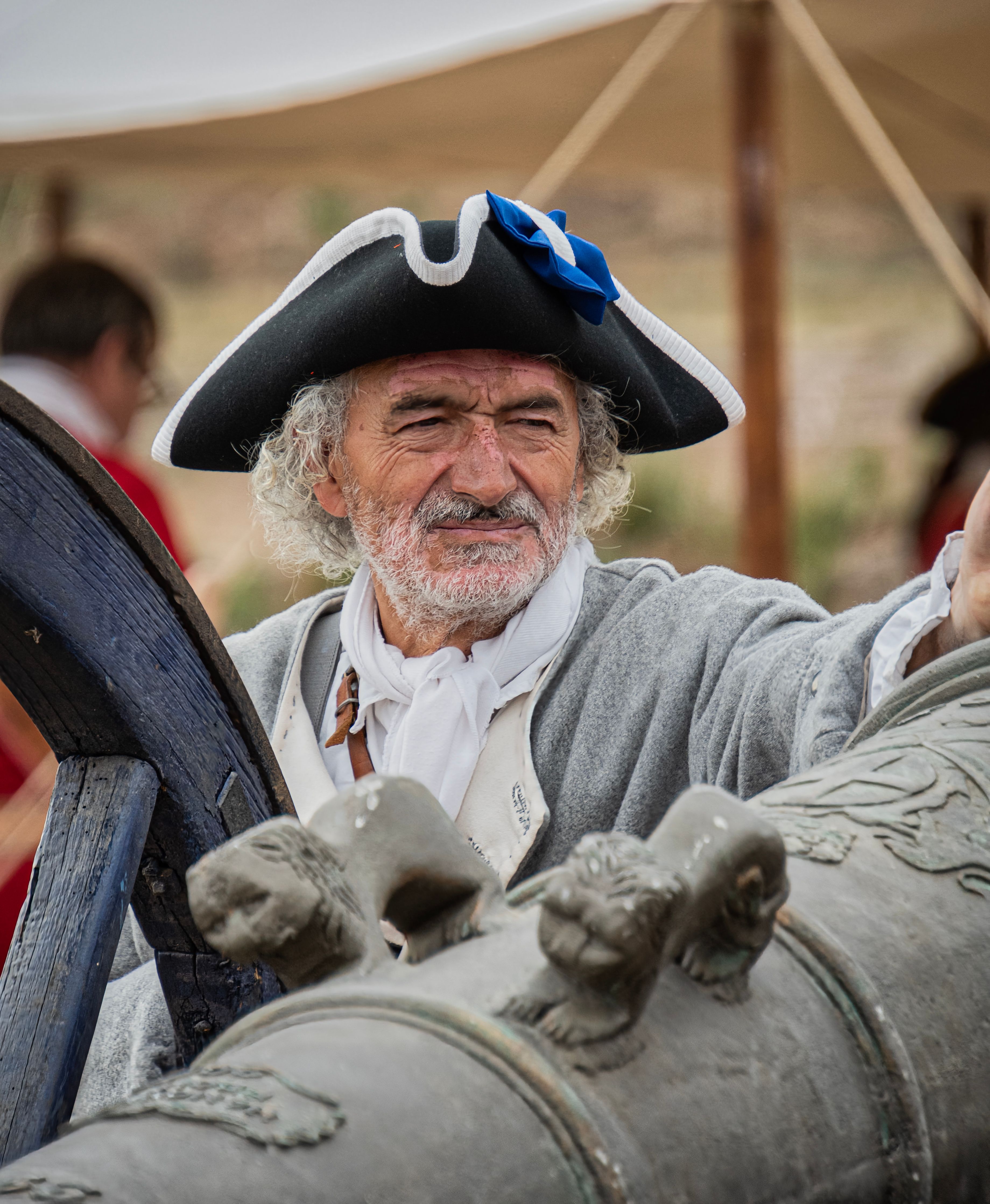 Elderly man in historical soldier uniform posing with a cannon during a reenactment event in Almansa, Spain.