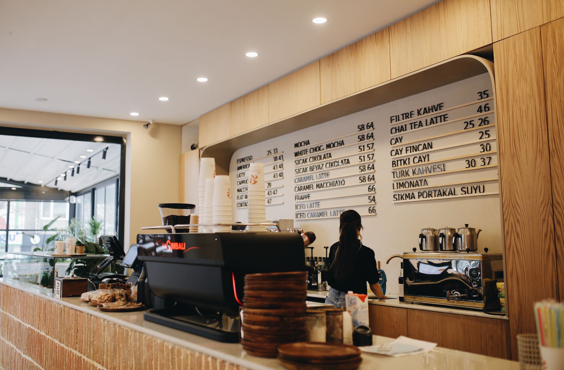 Contemporary café interior with a barista and espresso machine, showcasing a modern menu display.