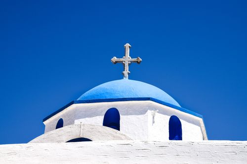 Free A traditional Greek Orthodox church with a blue dome and cross against a clear sky in Paros, Greece. Stock Photo