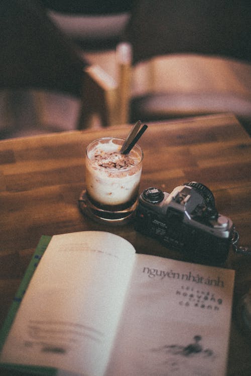 Плоская фотография камеры, книги и молока на столе