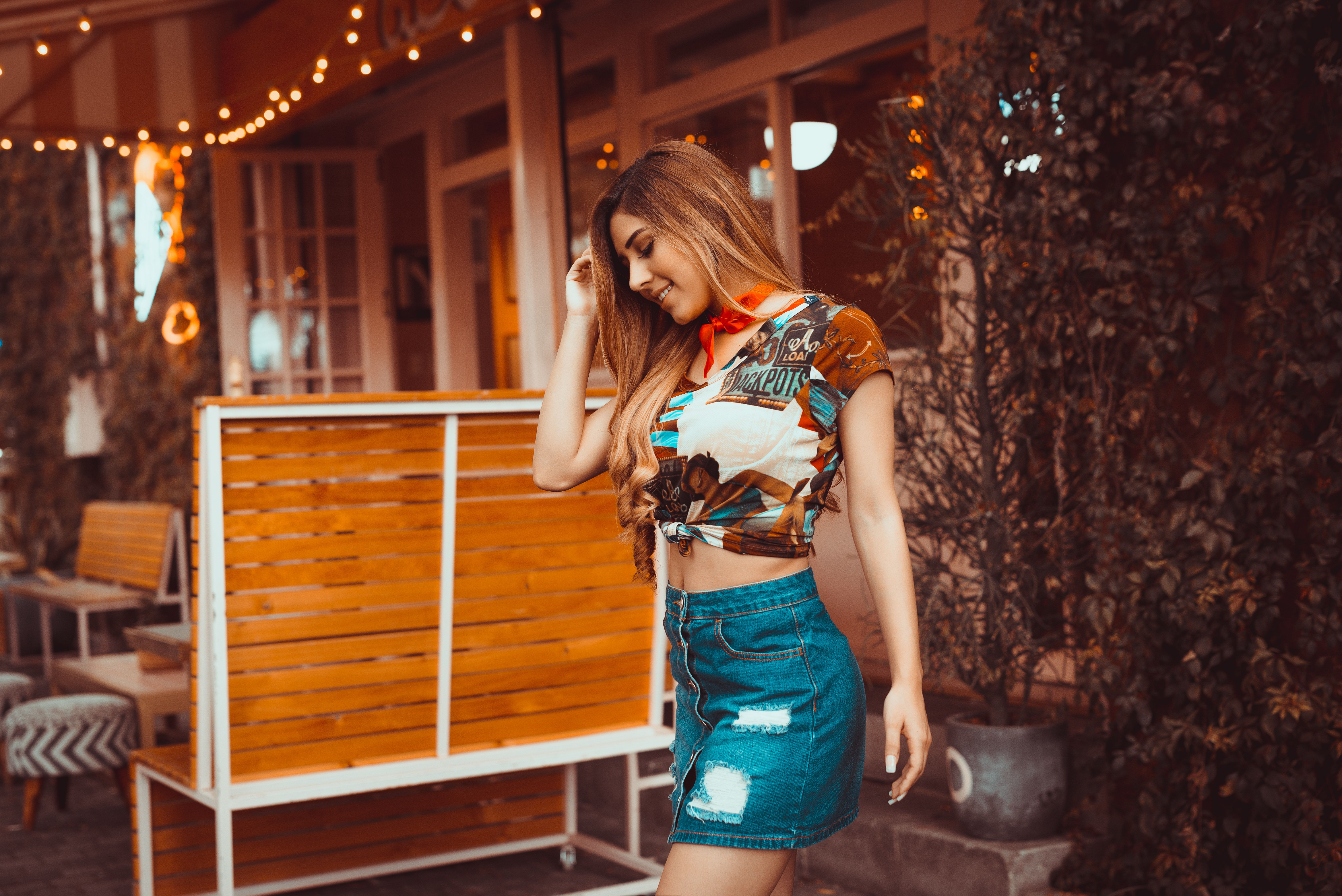 Young woman posing outdoors in casual fashion, wearing a denim skirt.