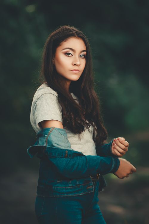 Free Portrait of a young woman in casual denim jacket in an outdoor setting. Stock Photo