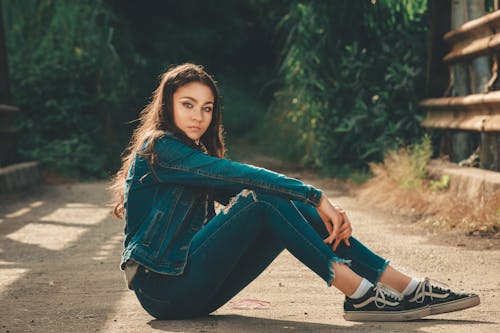 Young Brunette in a Denim Outfit Sitting on the Ground 
