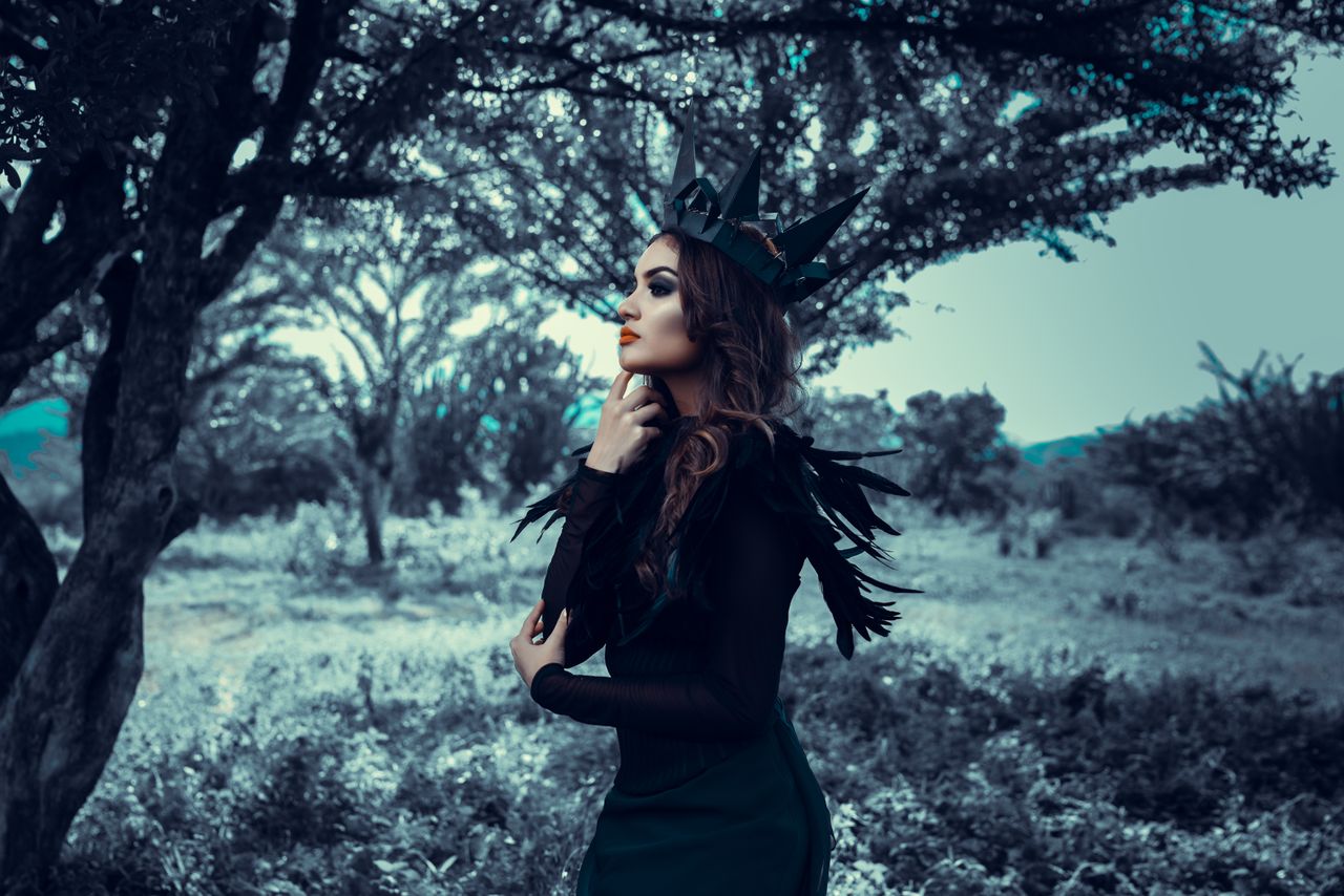 elegant woman with dark crown posing stylishly in a mystical forest se