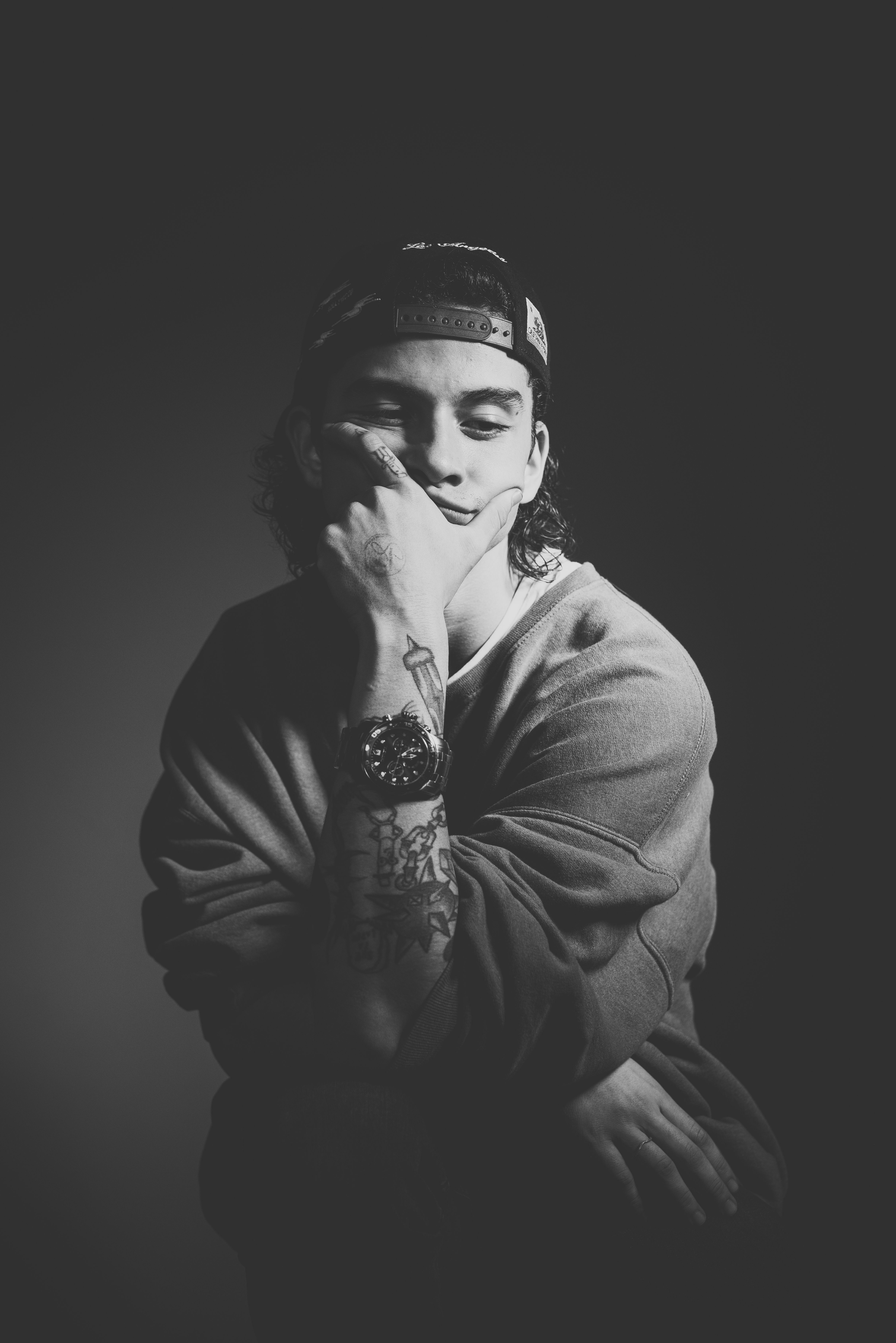 Monochrome portrait of a young man posing casually in a studio setting.