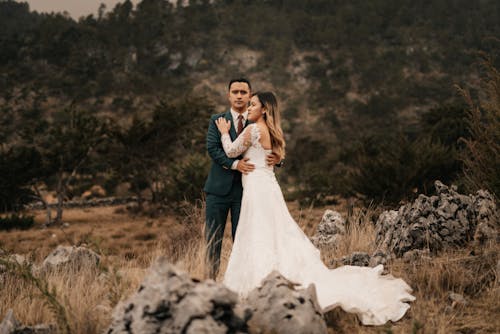 Newlywed Couple Standing on Meadow among Rocks