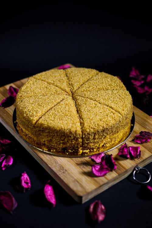 Free A beautifully sliced cake on a wooden board with vibrant rose petals. Stock Photo