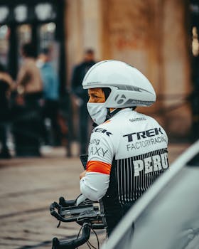 A professional cyclist wearing sports gear and helmet, preparing for a cycling race.