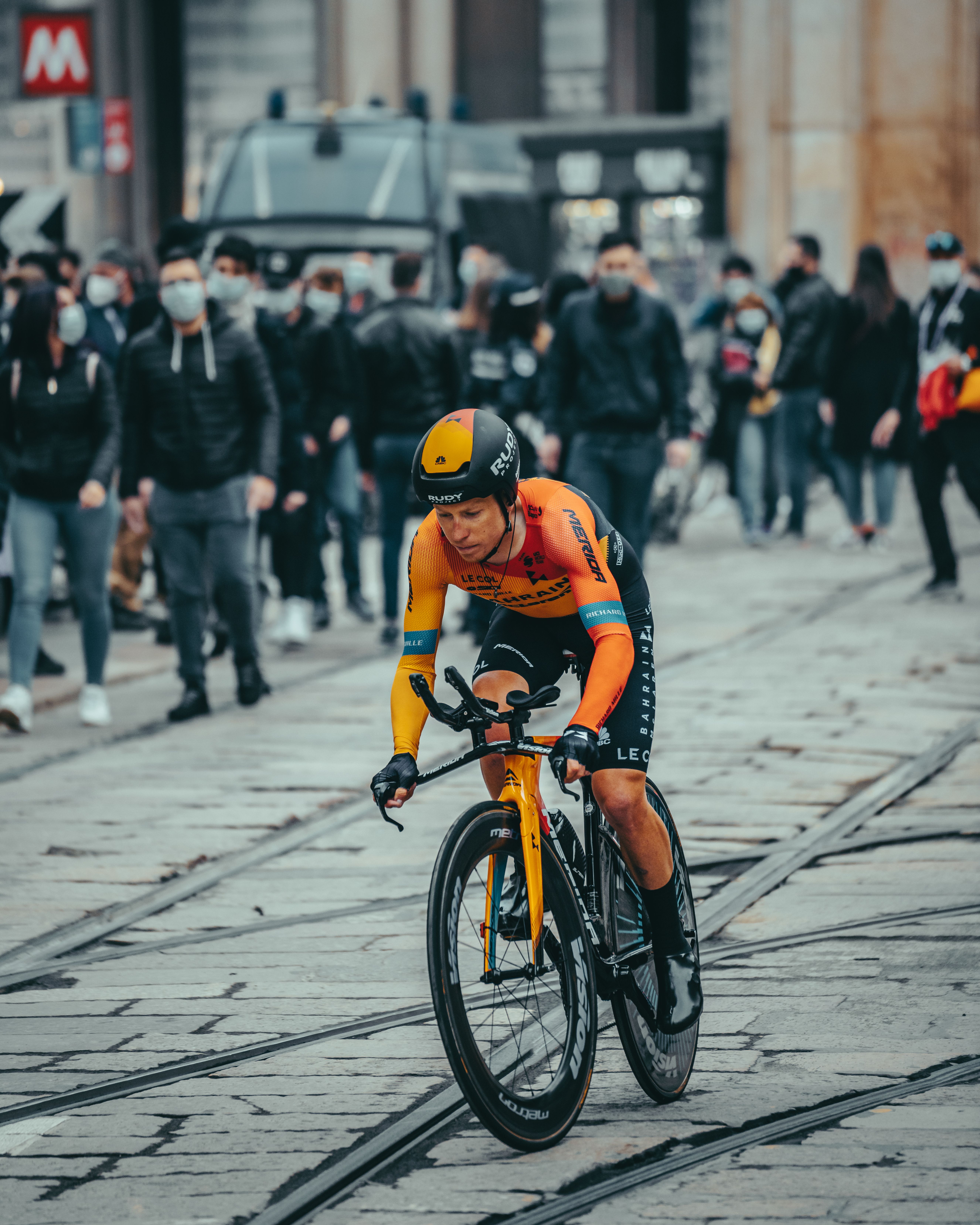 Professional cyclist competing in an urban street race surrounded by spectators.