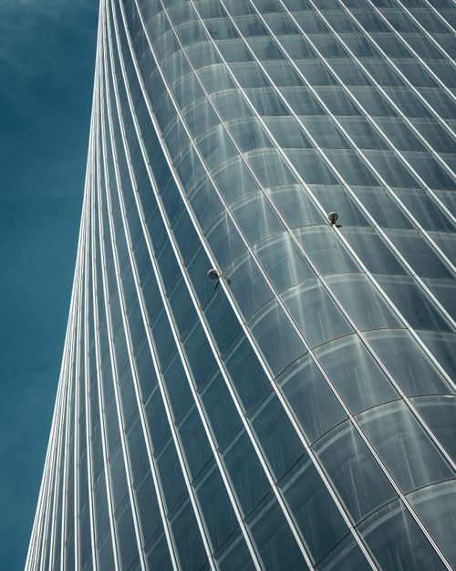 Free A low-angle vertical shot of a curved glass skyscraper showcasing modern architecture and urban design. Stock Photo
