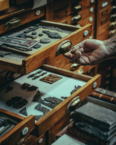 Hand pulling open a drawer of metal type in a print shop — photo by Mikita Yo on Pexels