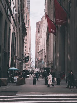 Urban street view of Wall Street in New York, showcasing iconic buildings and city life.