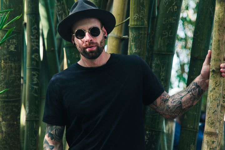 Man Holding Bamboo Plant Wearing Sunglasses and Fedora Hat
