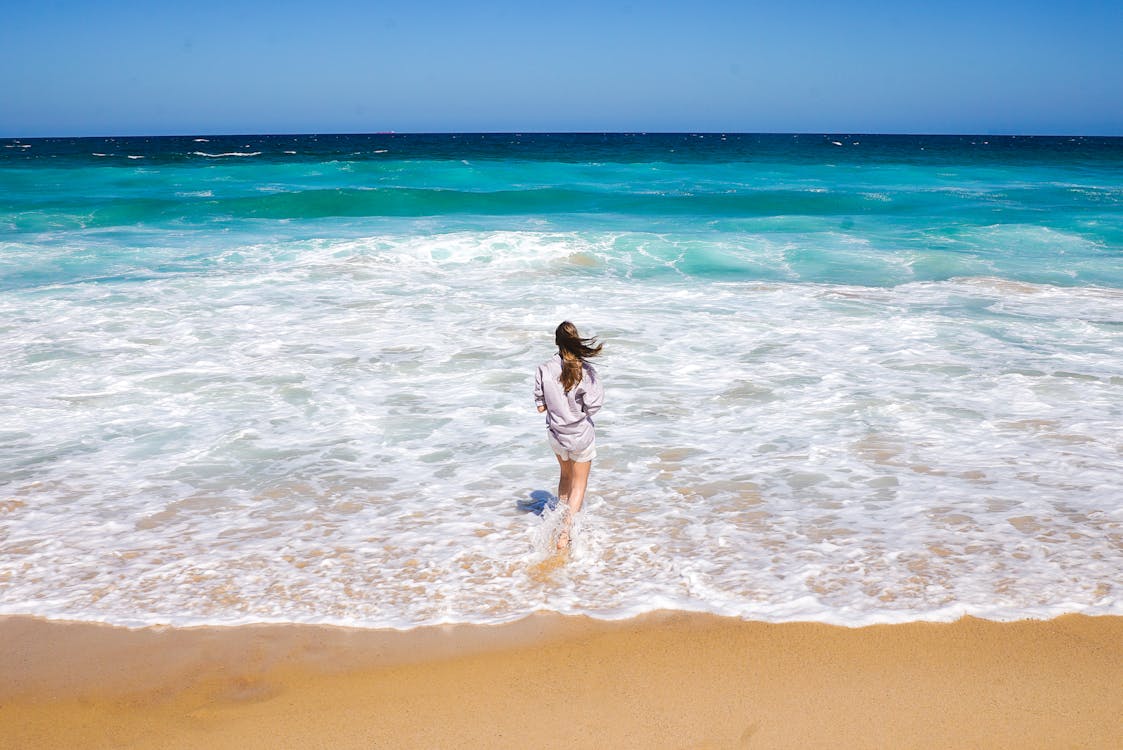 Foto Der Frau, Die Am Ufer Steht Und Horizont Betrachtet