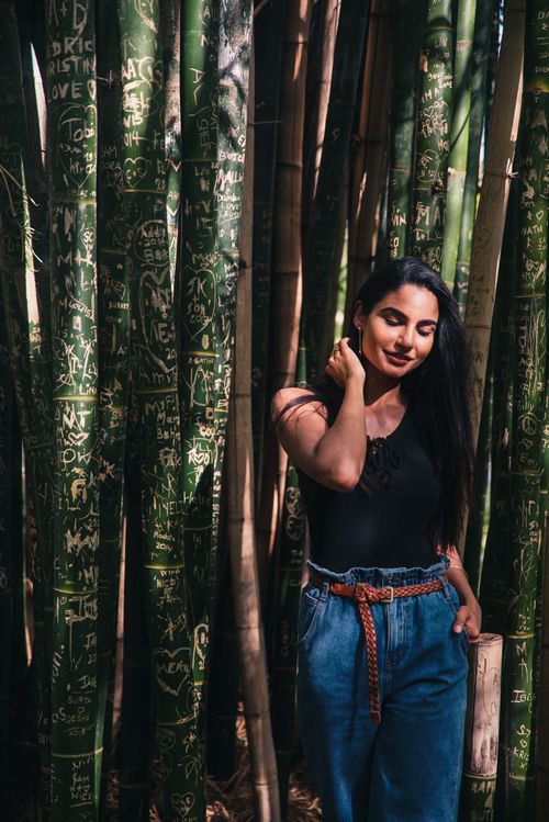 Free A woman stands confidently among engraved bamboo trees, showcasing natural beauty and style. Stock Photo
