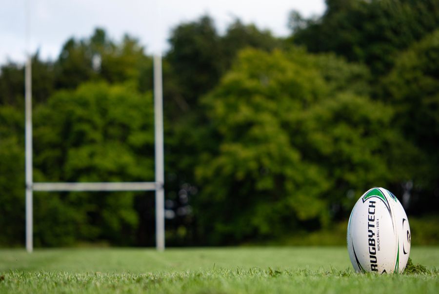 Rugby ball on a field with goalposts behind it