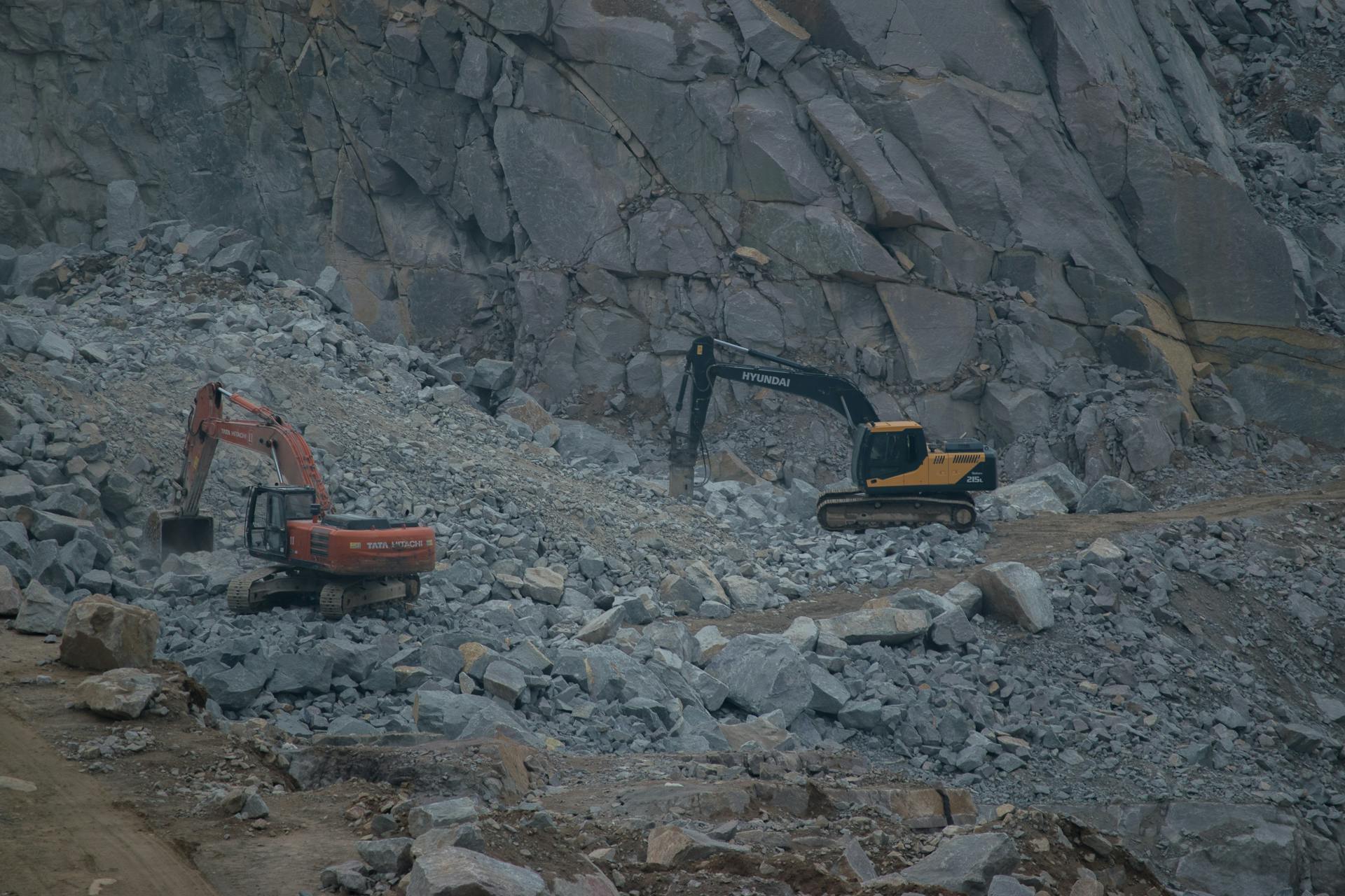 Dynamic construction site featuring excavators working on rocky terrain.