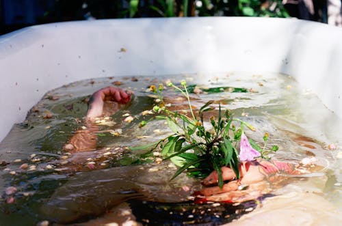 Woman Lying Down under Water with Flowers