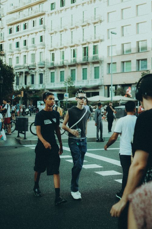 Free Young adults walking through a bustling urban street, showcasing dynamic city life. Stock Photo