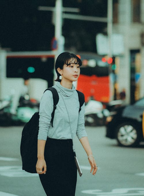 Young Woman with a Backpack Walking in City