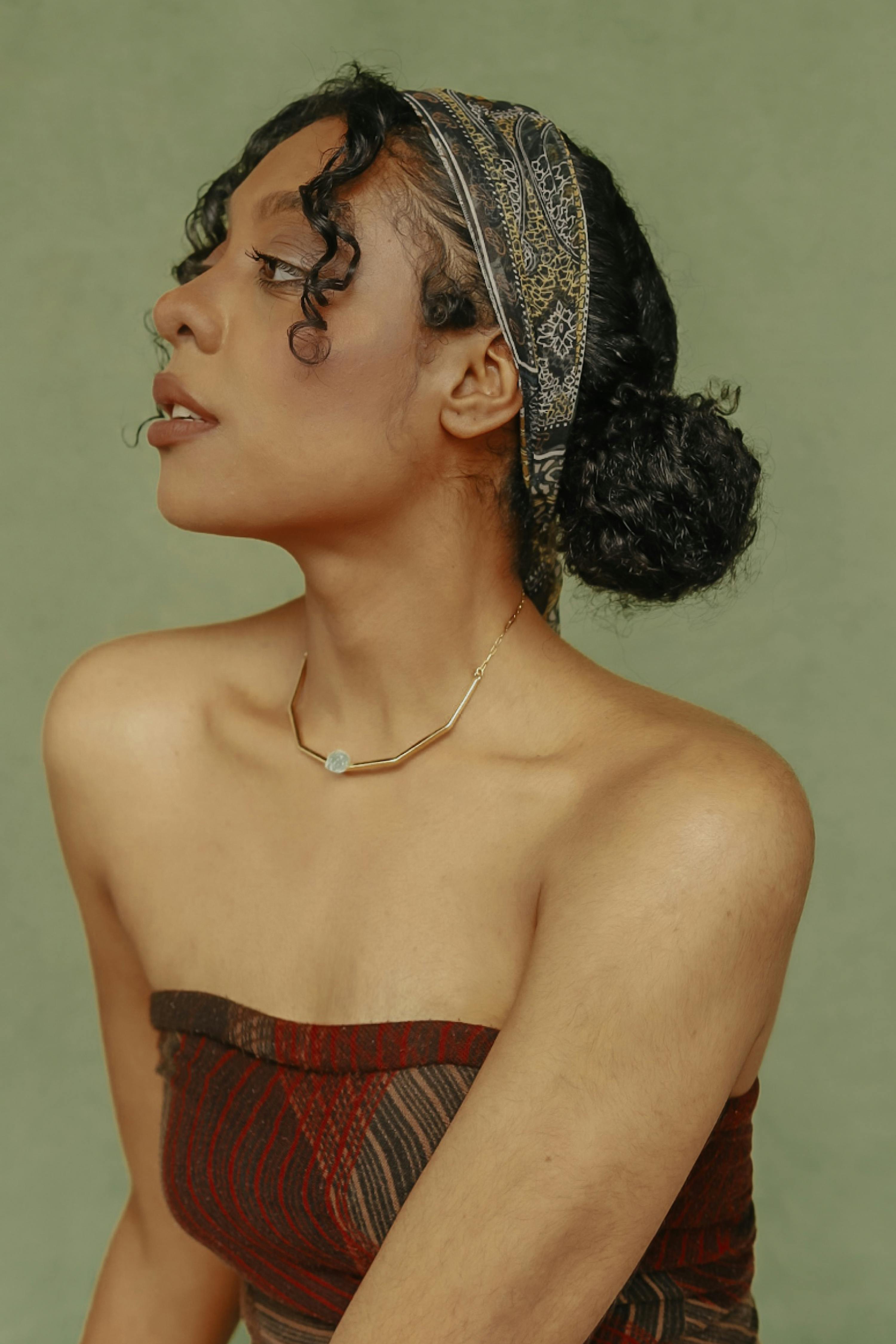 Stylish studio portrait of a young woman wearing a patterned headband and strapless top.